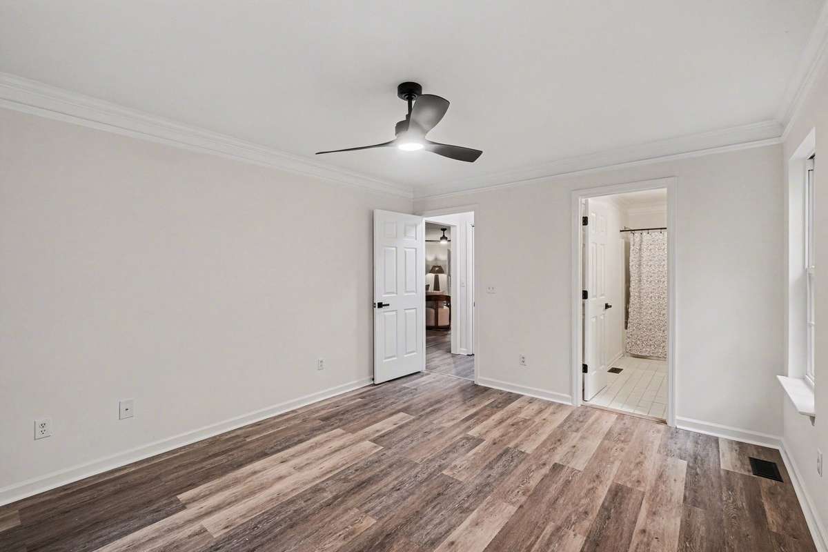 Relax in a spacious bedroom featuring brand-new, modern flooring and fresh interior paint. This retreat is accented by stylish crown molding, a contemporary ceiling fan, and double closets with upgraded matte black hardware for a clean, designer look