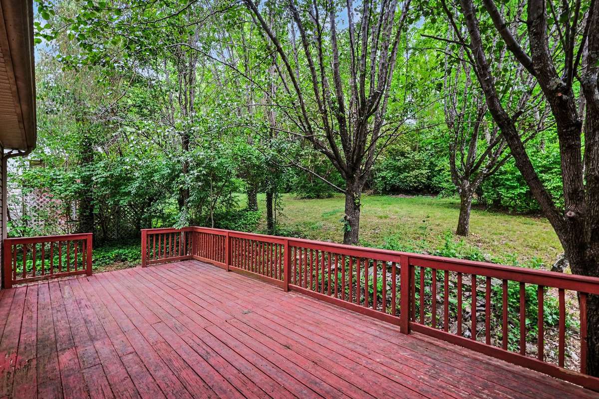 Private back deck overlooking a serene, wooded common area. This spacious outdoor living space is ideal for relaxing and enjoying the mature greenery that surrounds this move-in-ready home.