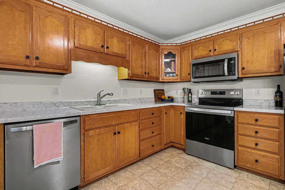 Update-heavy kitchen featuring brand-new appliances, a modern statement light fixture, and upgraded door hardware. The bright space includes plenty of cabinetry and a convenient built-in workspace.
