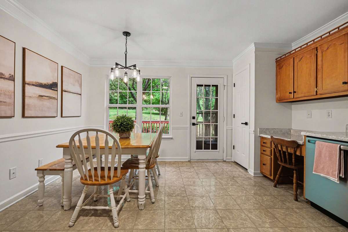 Bright dining area featuring updated lighting and fresh neutral paint. The large windows and glass door provide plenty of natural light and easy access to the private outdoor deck.