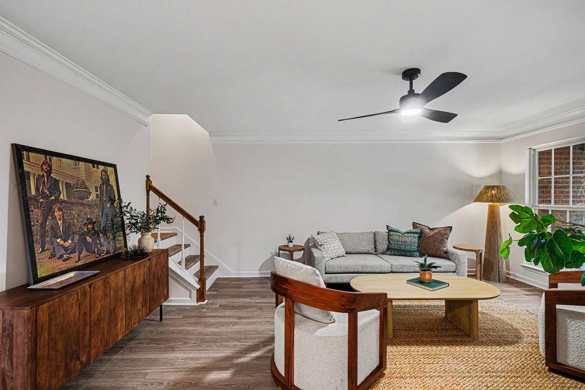 A closer look at the stunning updates, including the newly finished stair flooring and fresh interior paint. The crown molding and modern ceiling fan add a touch of sophistication to this bright, open living space.