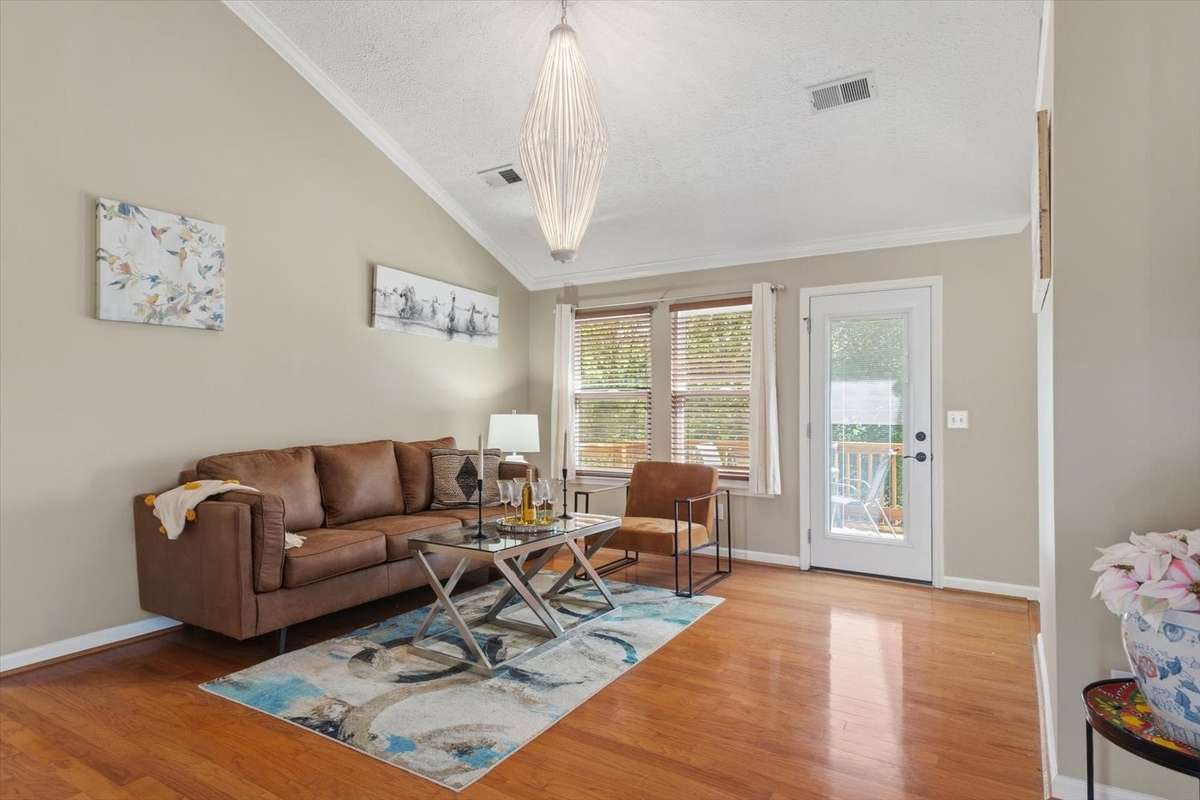 Expansive living room with tall ceilings off the dining room, kitchen, and back deck.