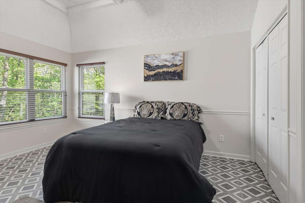 Primary bedroom with updated flooring, and tall ceilings.
