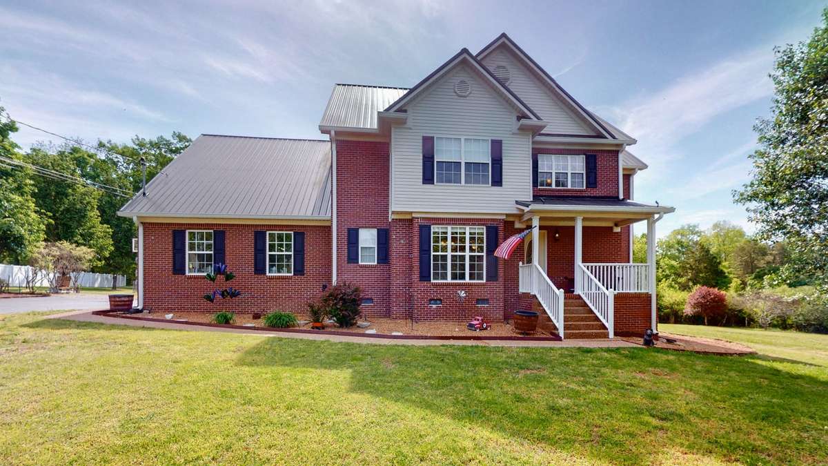 Beautiful estate home with metal roof and rocking chair front porch.