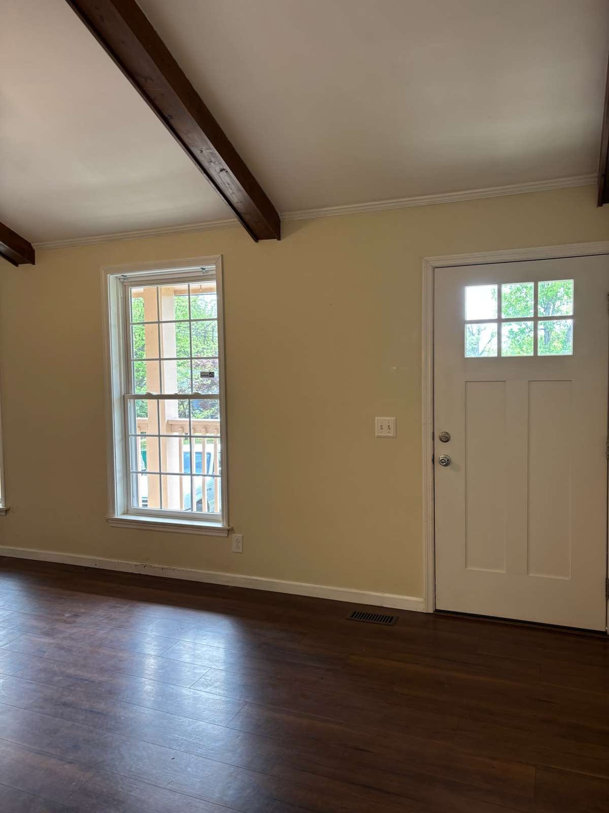 Living room with new LVT flooring, ceiling fan and ceiling beams on pitched ceiling.