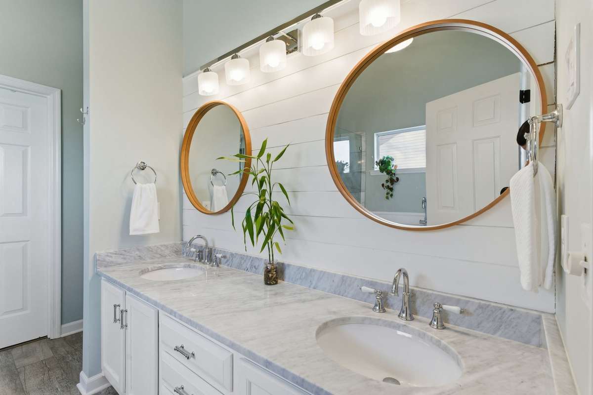Spa-inspired owner’s bathroom featuring a freestanding soaking tub, glass-enclosed tiled shower, dual vanities with marble countertops, and abundant natural light—designed for everyday ease and quiet luxury.