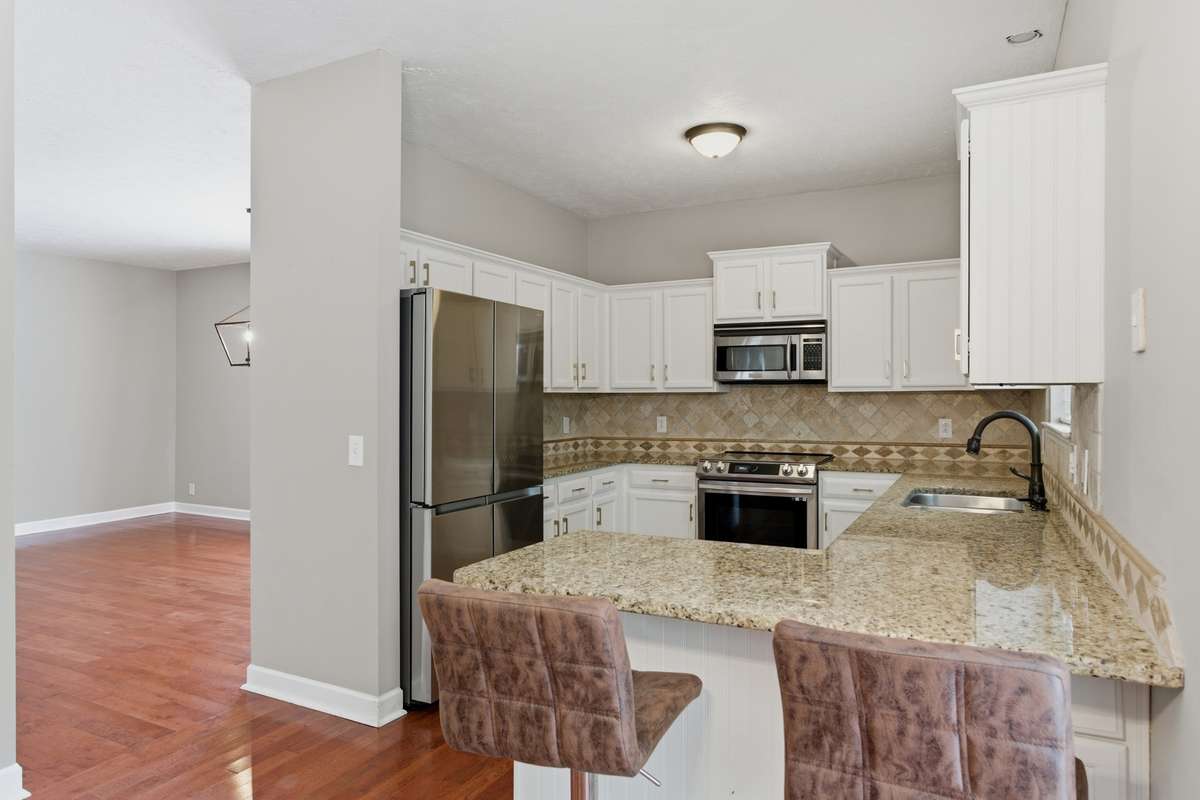 Bright, updated kitchen featuring white cabinetry, granite countertops, and new high-end stainless appliances, including an induction range with air-fry capability. Designed for both everyday function and effortless entertaining.