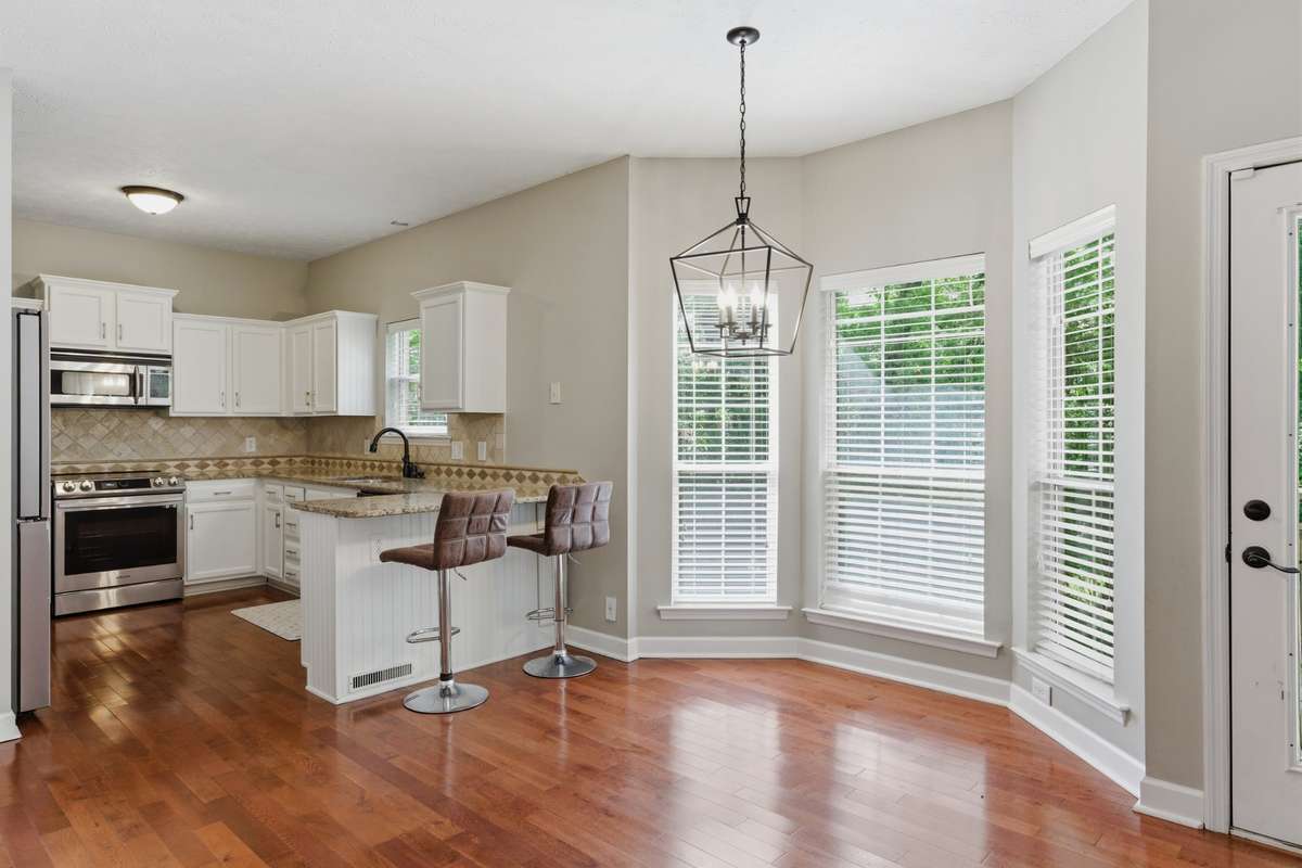 Sunlit breakfast nook with oversized windows and warm hardwood floors, offering a bright, inviting space for casual meals, morning coffee, or a cozy dining area just off the kitchen.