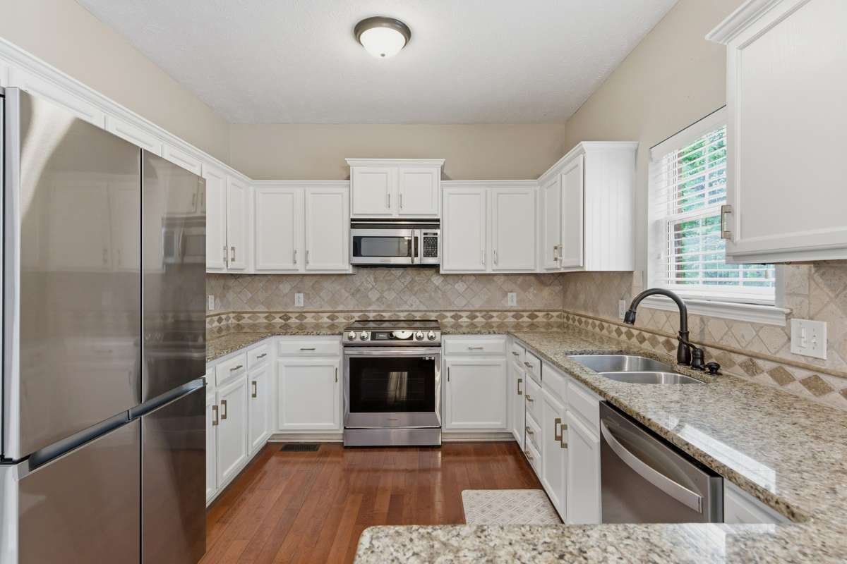 Bright, updated kitchen featuring white cabinetry, granite countertops, and new high-end stainless appliances, including an induction range with air-fry capability. Designed for both everyday function and effortless entertaining.