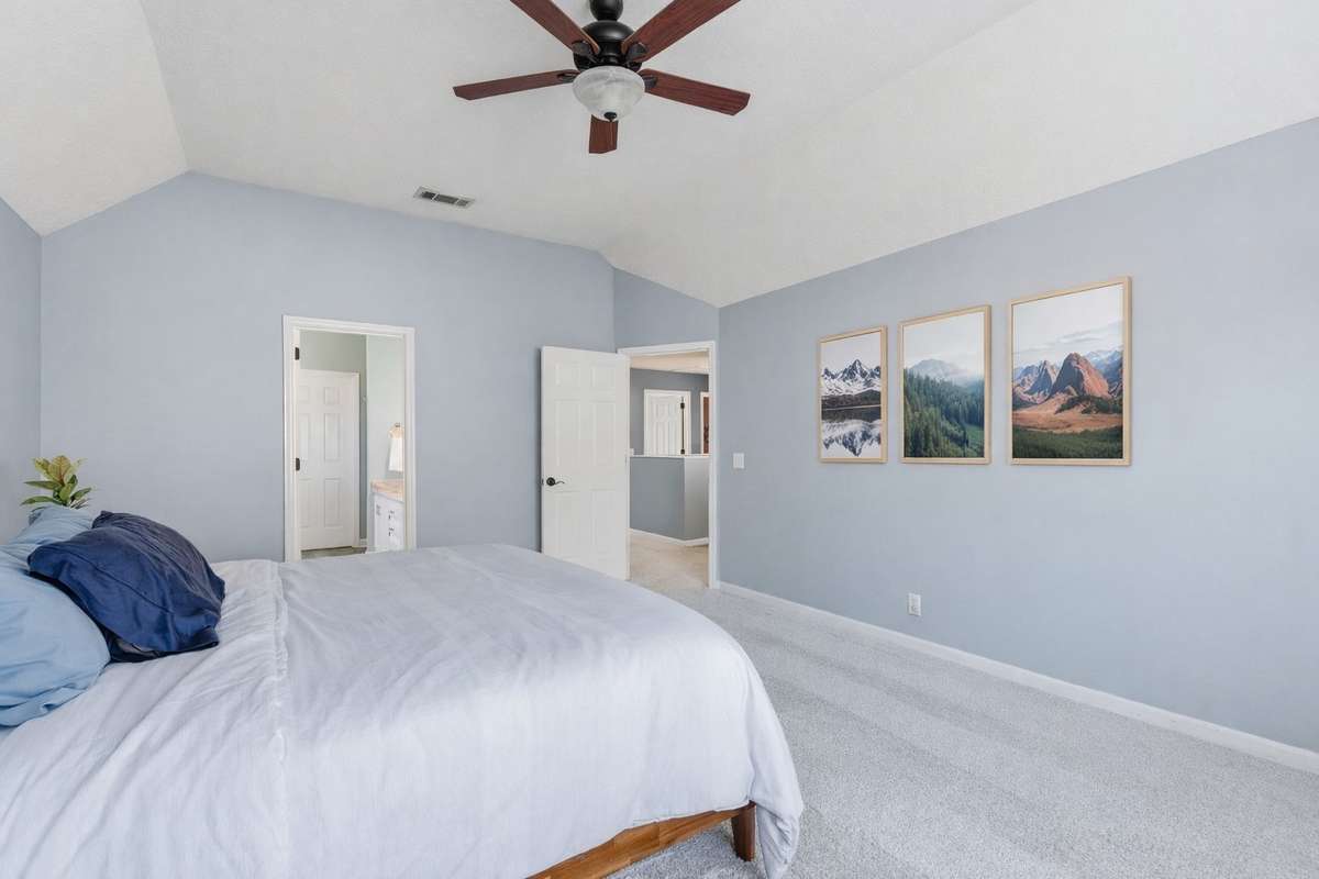Light-filled owner’s bedroom with vaulted ceilings, soft neutral tones, and an arched window. Directly connected to the owner’s bathroom and walk-in closet for comfort, privacy, and everyday ease. - Virtually staged