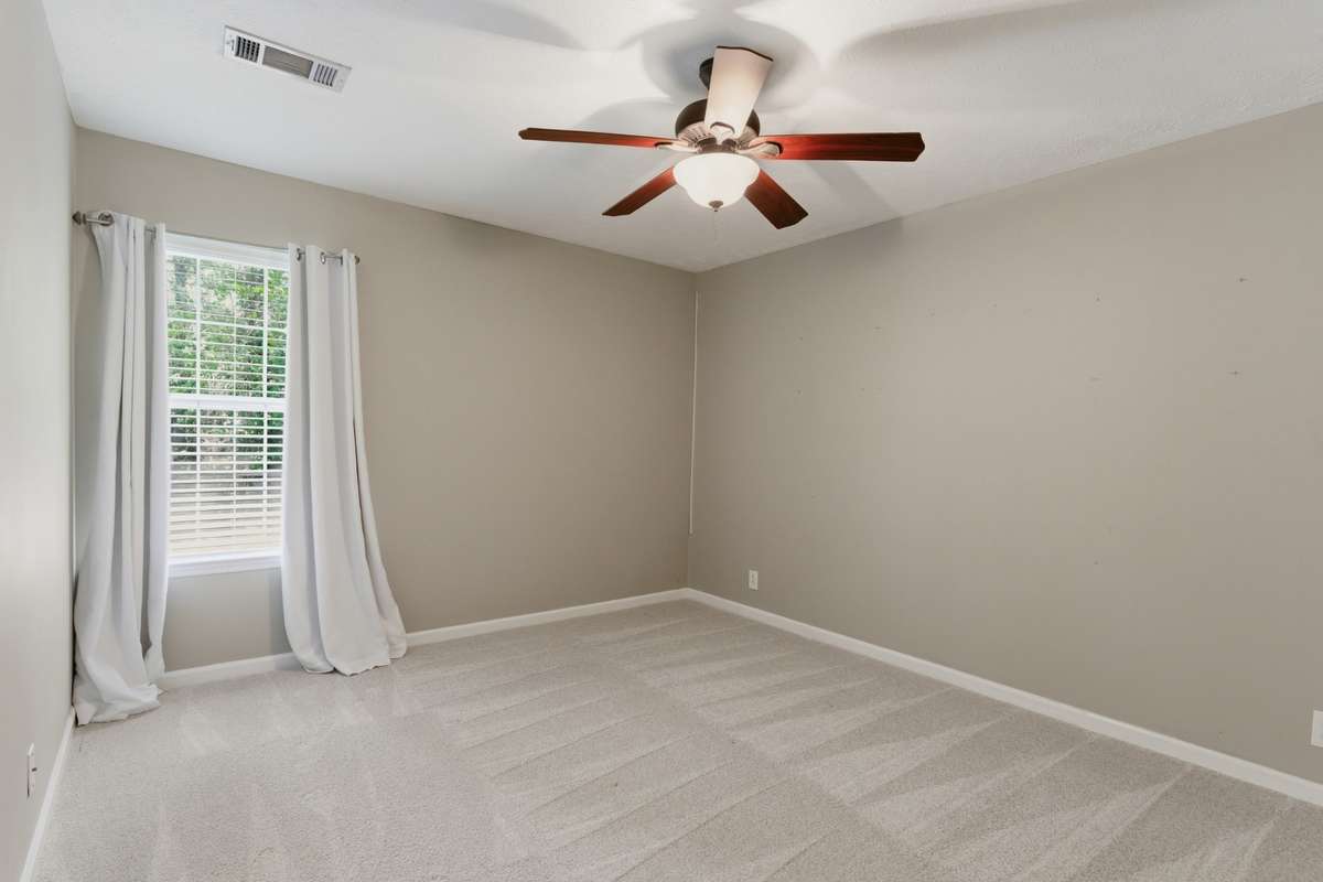 Spacious third bedroom with plush carpet, ceiling fan, and a walk-in closet. Bright and comfortable with a flexible layout ideal for guests, family, or a dedicated home office.