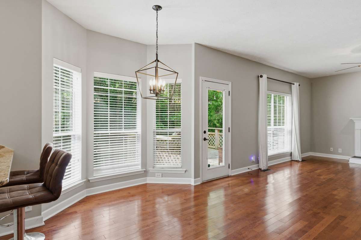 Sunlit breakfast nook with oversized windows and warm hardwood floors, offering a bright, inviting space for casual meals, morning coffee, or a cozy dining area just off the kitchen.
