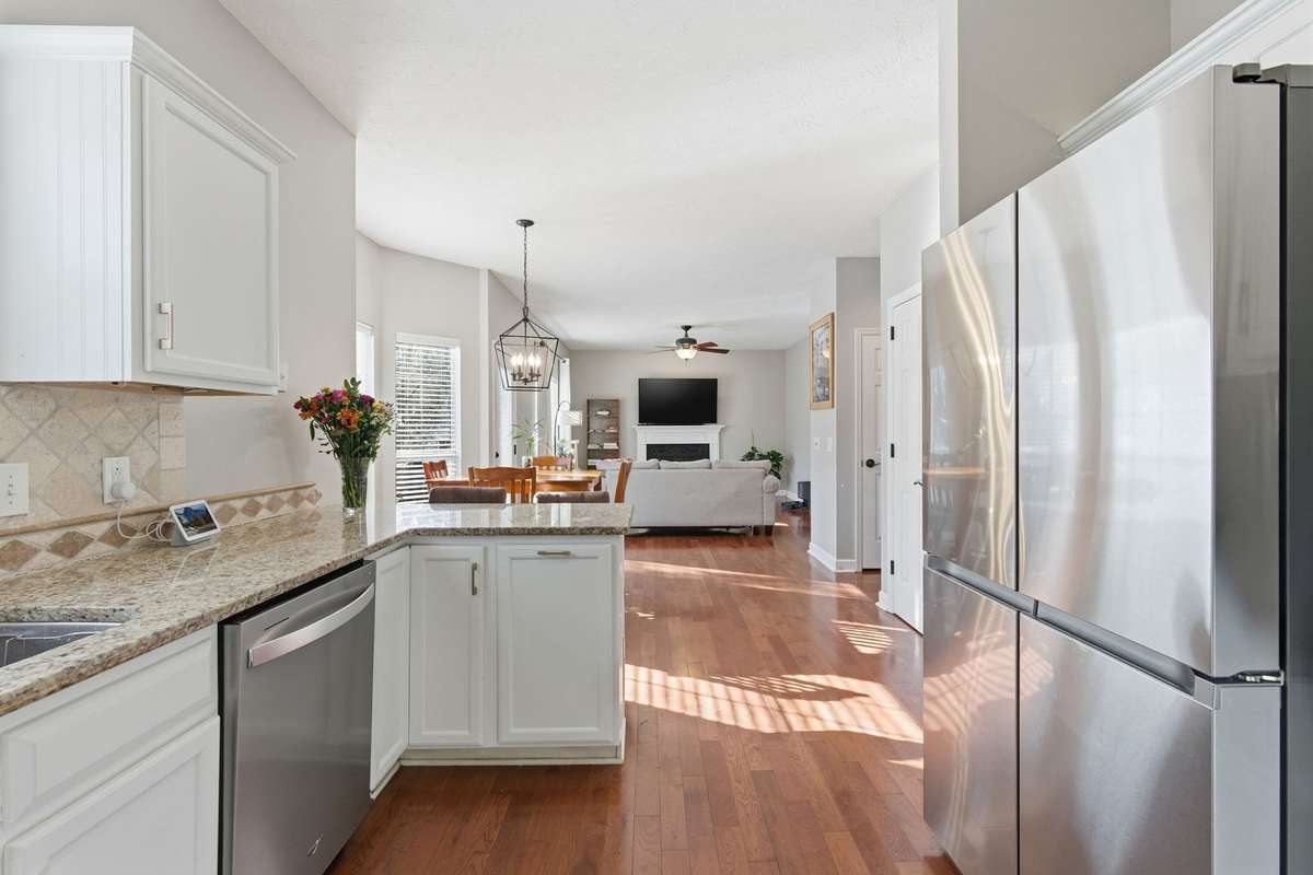 Bright, updated kitchen featuring white cabinetry, granite countertops, and new high-end stainless appliances, including an induction range with air-fry capability. Designed for both everyday function and effortless entertaining.