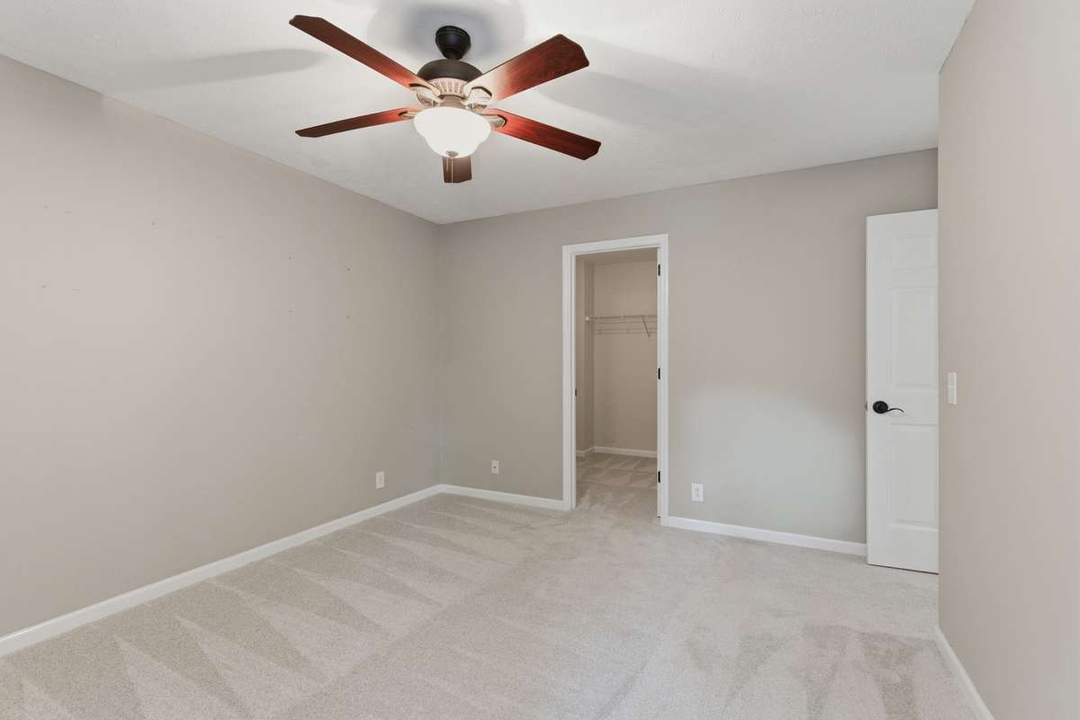 Spacious third bedroom with plush carpet, ceiling fan, and a walk-in closet. Bright and comfortable with a flexible layout ideal for guests, family, or a dedicated home office.
