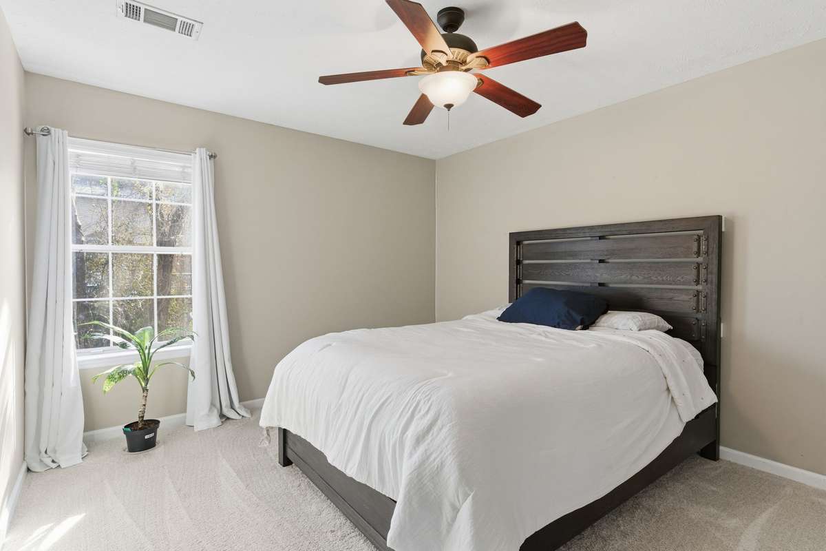 Spacious third bedroom with plush carpet, ceiling fan, and a walk-in closet. Bright and comfortable with a flexible layout ideal for guests, family, or a dedicated home office.