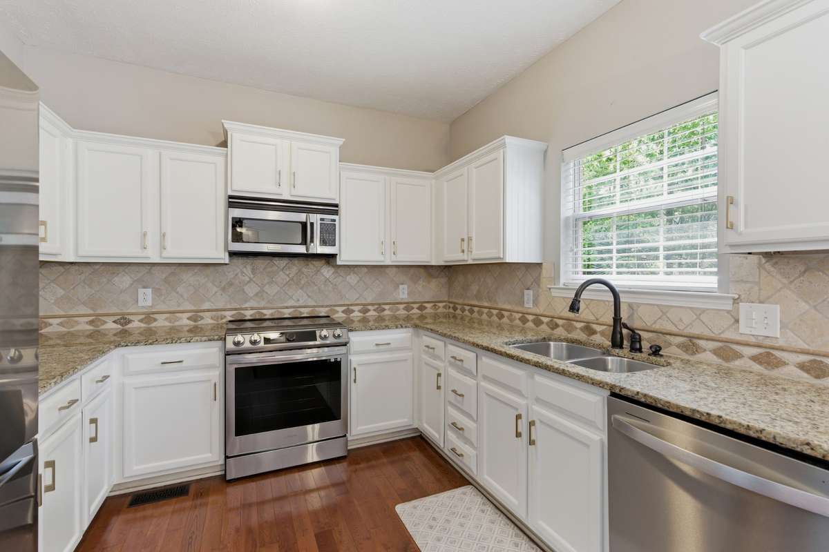 Bright, updated kitchen featuring white cabinetry, granite countertops, and new high-end stainless appliances, including an induction range with air-fry capability. Designed for both everyday function and effortless entertaining.