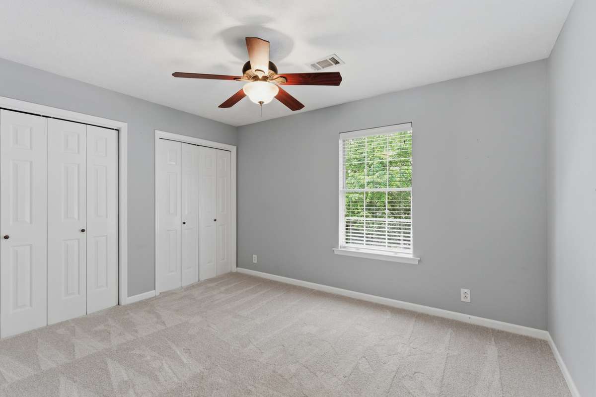 Bright second bedroom with plush carpet, ceiling fan, and generous closet space—ideal for a guest room, home office, or flex space with natural light and a quiet second-level setting.