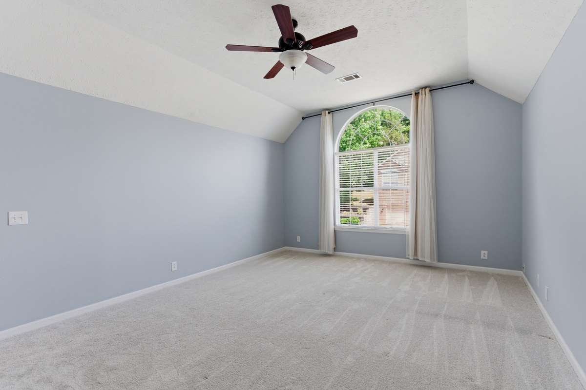 Light-filled owner’s bedroom with vaulted ceilings, soft neutral tones, and an arched window. Directly connected to the owner’s bathroom and walk-in closet for comfort, privacy, and everyday ease.