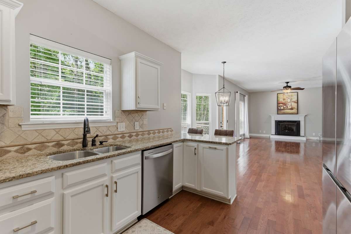 Bright, updated kitchen featuring white cabinetry, granite countertops, and new high-end stainless appliances, including an induction range with air-fry capability. Designed for both everyday function and effortless entertaining.