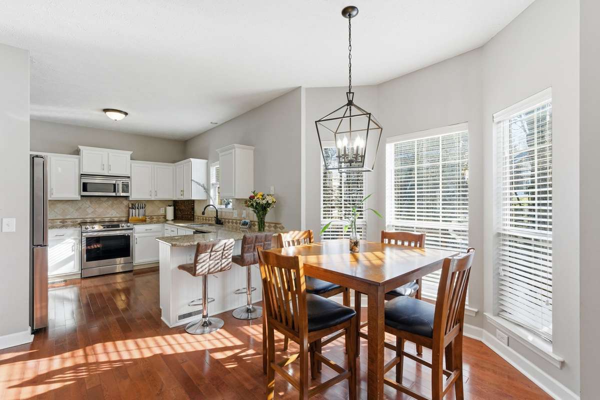 Sunlit breakfast nook with oversized windows and warm hardwood floors, offering a bright, inviting space for casual meals, morning coffee, or a cozy dining area just off the kitchen.