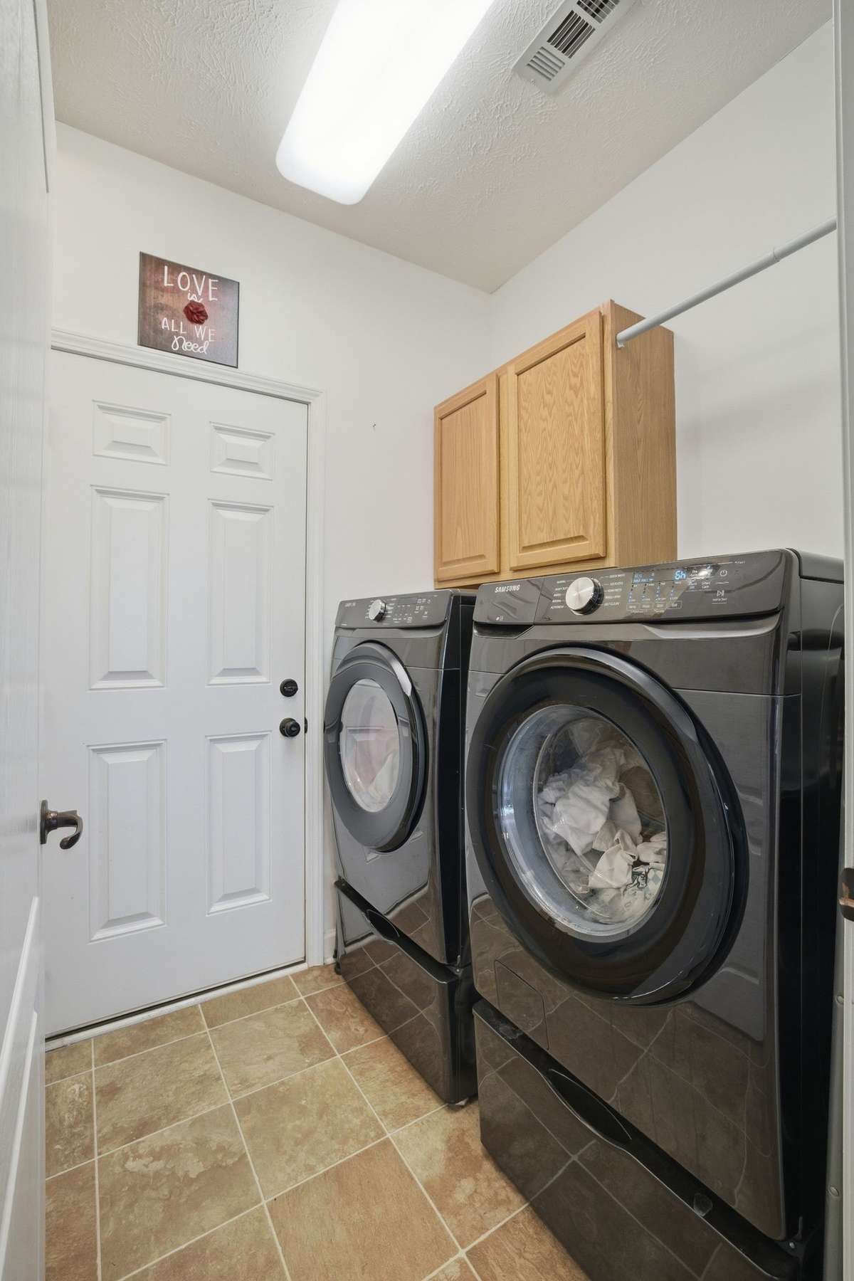 The laundry room is located between the garage and the kitchen. The laundry room features built in cabinets with a hanging bar and a sink (not shown in photo).