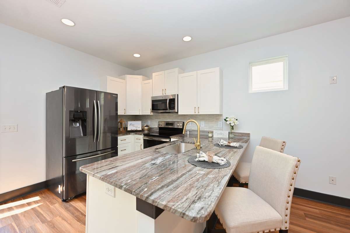 Gleaming granite counters with freshly painted white cabinets, new hardware and stainless steel appliances