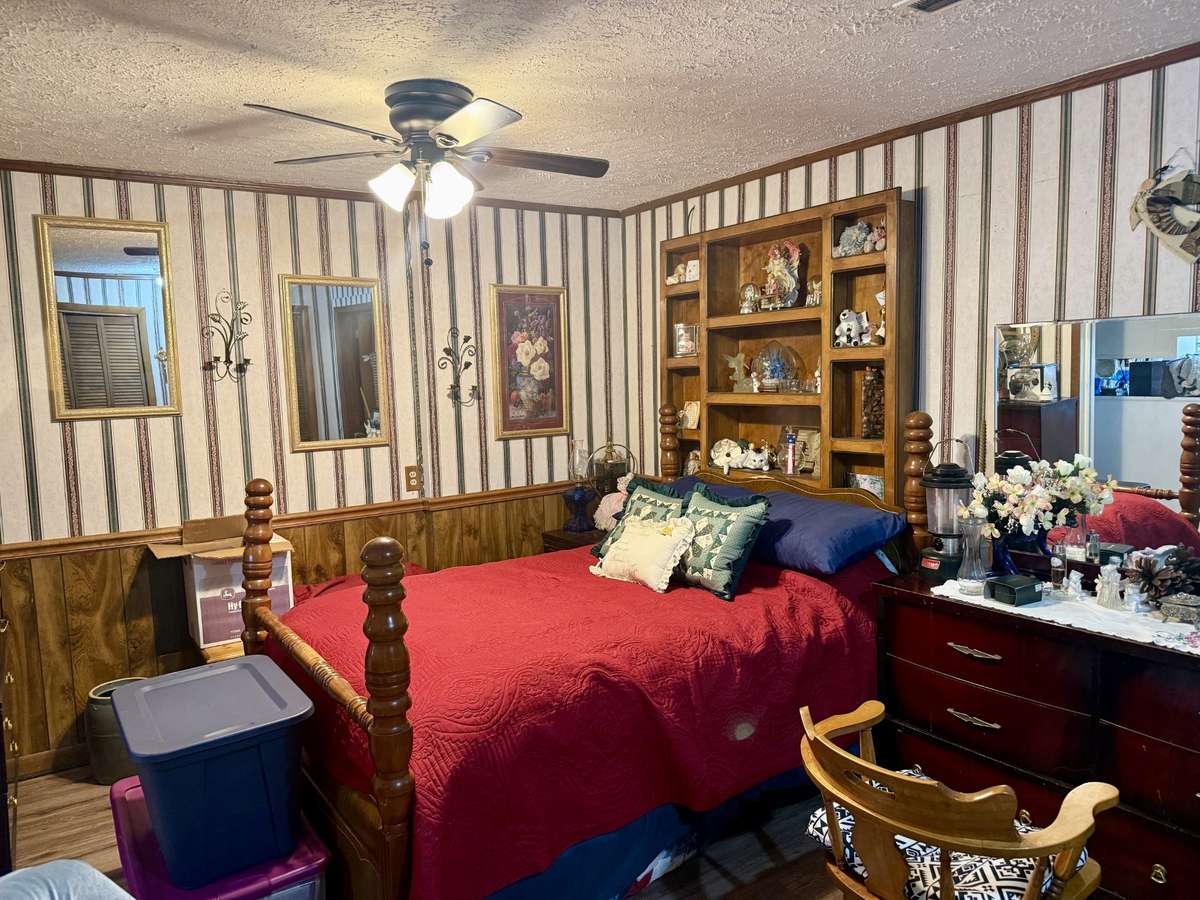 First bedroom with vinyl flooring and ceiling fan.