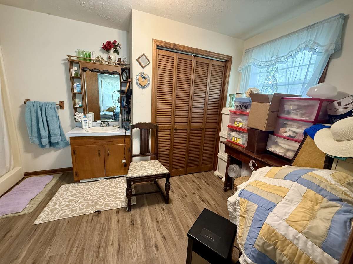Primary bath with vinyl flooring, single vanity, closet and shower.