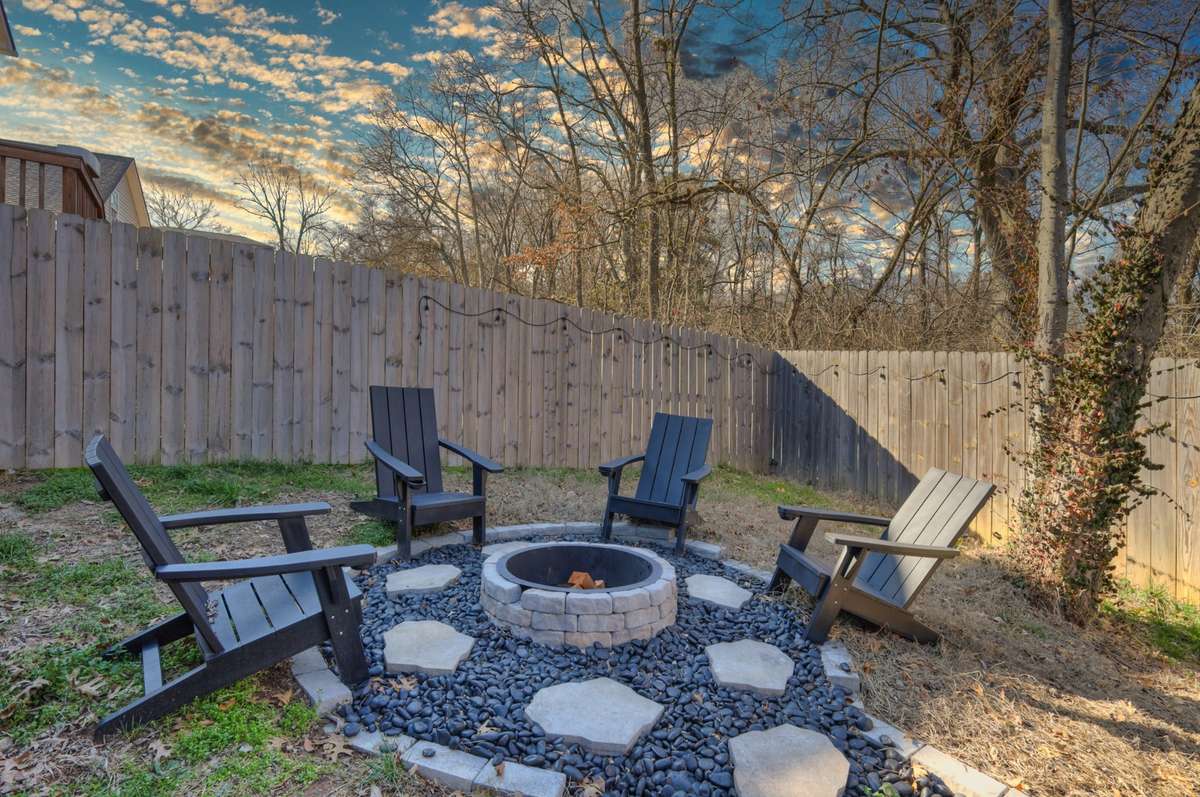 The back yard that features a fire pit and area for a grill. The back yard has a privacy fence.