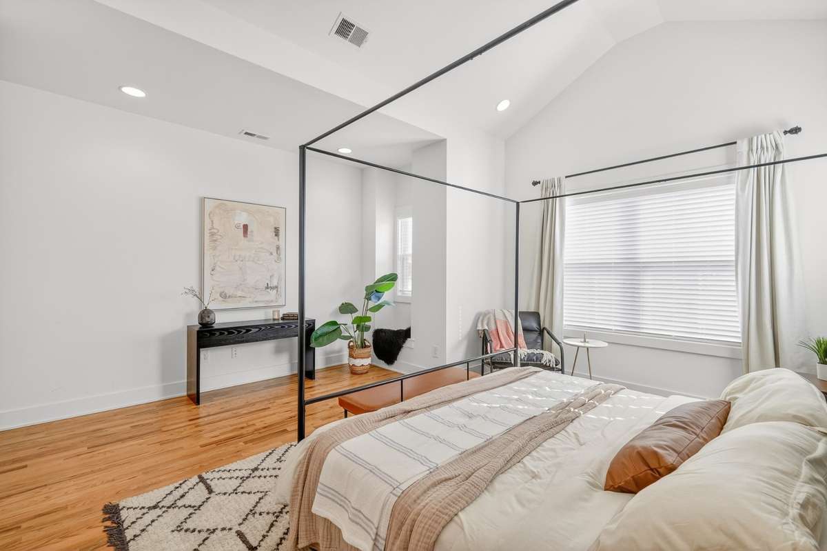 Primary Bedroom En-Suite with vaulted ceiling, multiple windows, recessed lighting and ceiling fan. Custom trim accent wall. Hardwood floors that lead into a private bath with double vanity and walk-in glass shower. Large walk-in closet.
