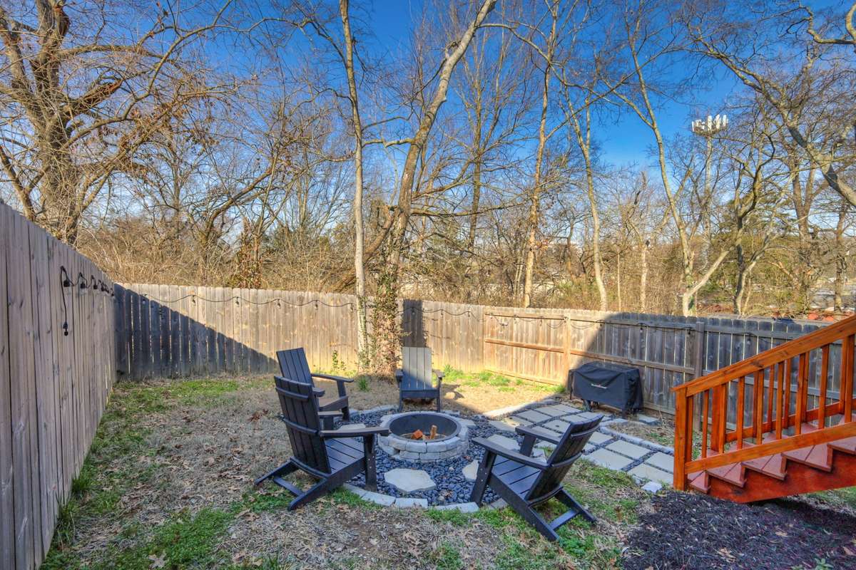 The back yard that features a fire pit and area for a grill. The back yard has a privacy fence.