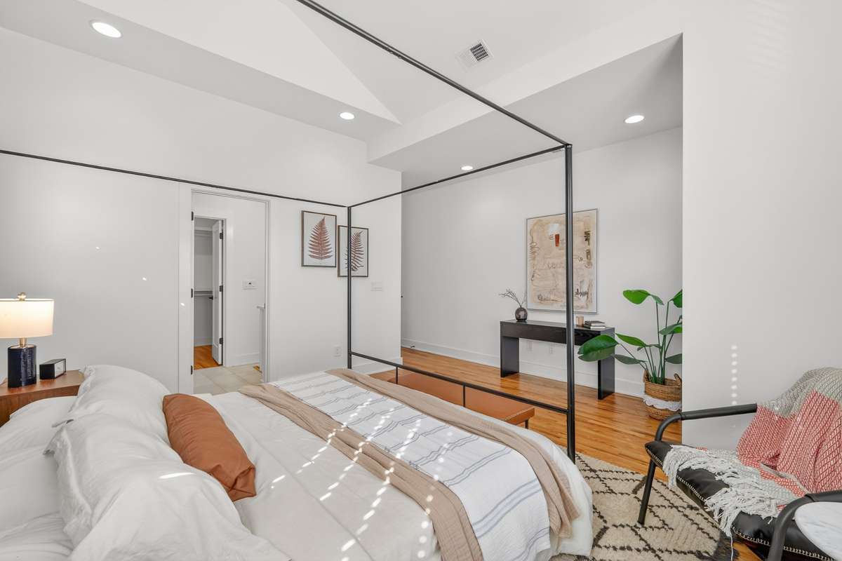 Primary Bedroom Ensuite with vaulted ceiling, multiple windows, recessed lighting and ceiling fan. Custom trim accent wall. Hardwood floors that lead into a private bath with double vanity and walk-in glass shower. Large walk-in closet.