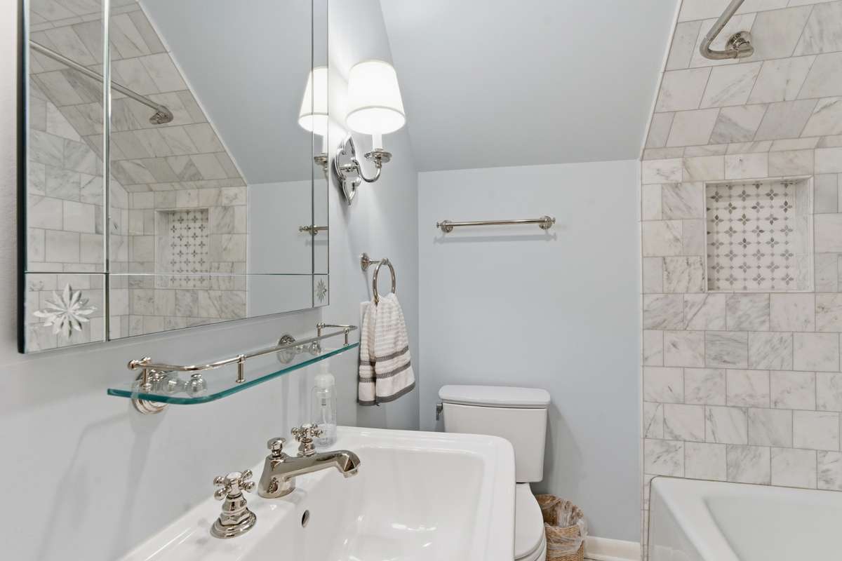 Full bath upstairs with marble tile and tub.