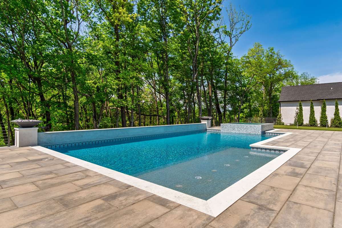 View of backyard with POOL & SPA backs up to mature tree line.