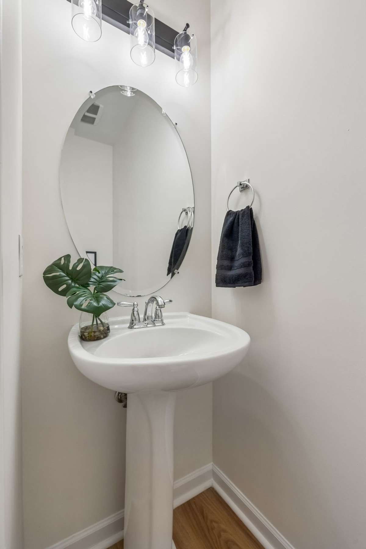Half bath for guests with new lighting, floors, and commode.