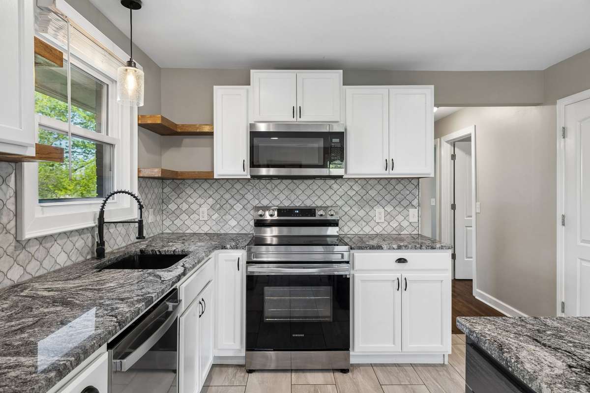 Beautiful kitchen with a spacious island, new granite countertops, tiled backsplash, and stainless steel appliances.