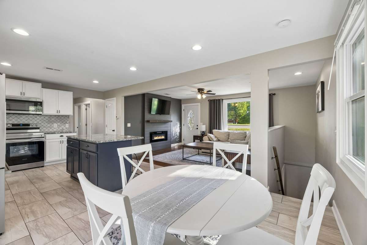 Spacious and bright open floor plan viewed from the back of the house, showcasing the seamless flow between the living room, dining/sitting area, and fully updated kitchen.