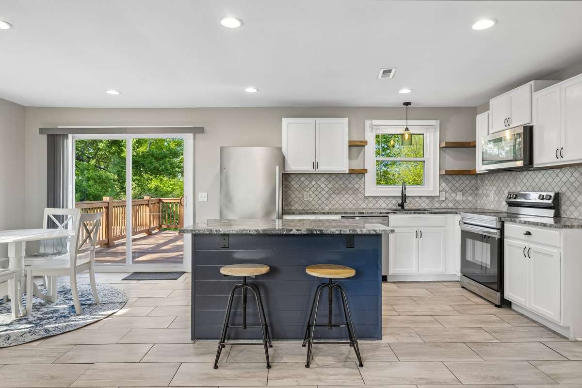 Gorgeous fully renovated kitchen featuring a large, beautiful island perfect for entertaining and everyday living. It boasts new granite countertops, a stylish tiled backsplash, fresh cabinetry, and high-end stainless steel appliances.