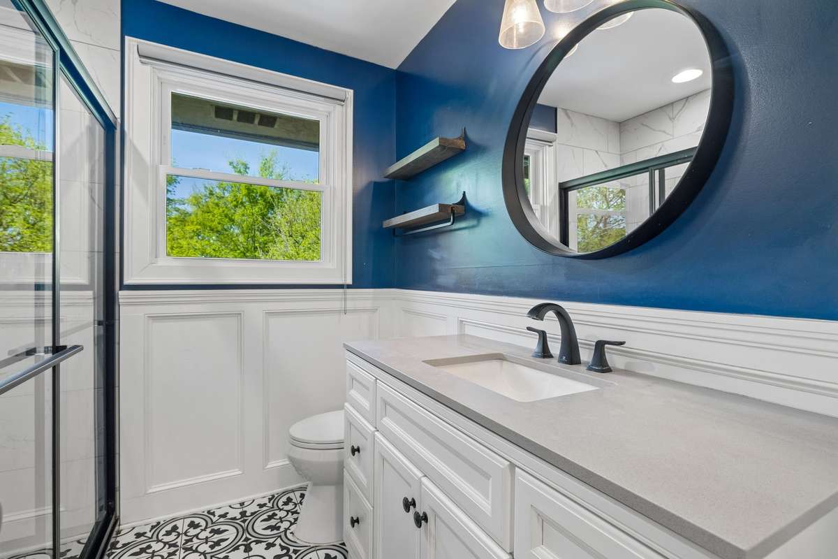 Beautifully gutted and rebuilt full bathroom featuring elegant wainscoting, detailed tile work, and durable tiled floors.