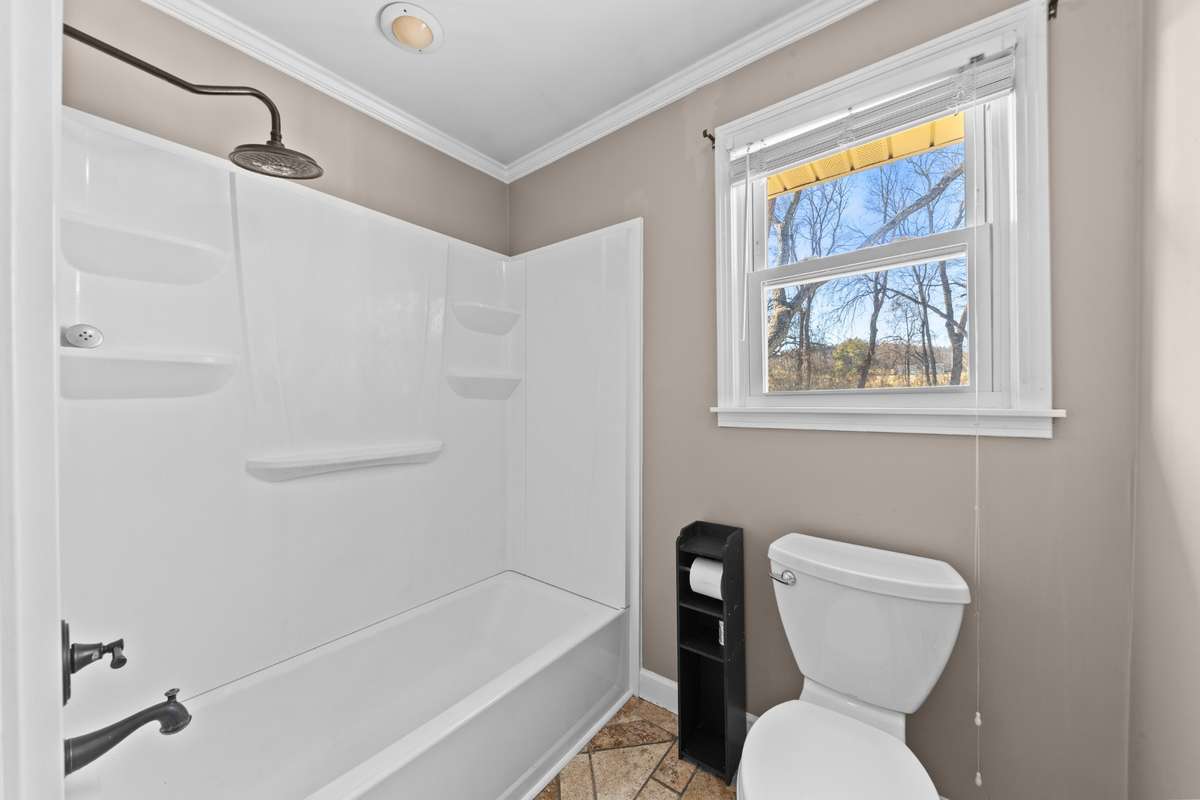 Primary shower/tub combo with a backyard view.