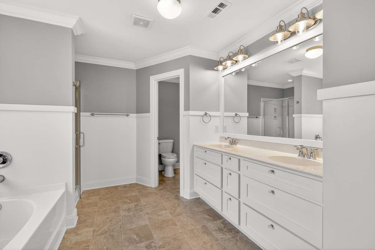 Primary bathroom with dual vanities and separate facility closet.