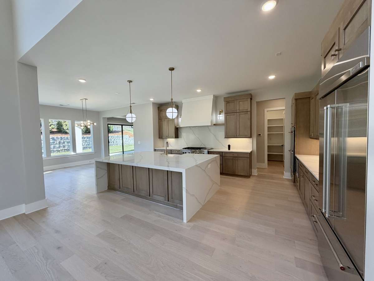 At the heart of the home, the gourmet kitchen, inviting great room, and exceptional indoor-outdoor living spaces come together to create the ultimate setting for hosting and connection.  Actual Home Photo.