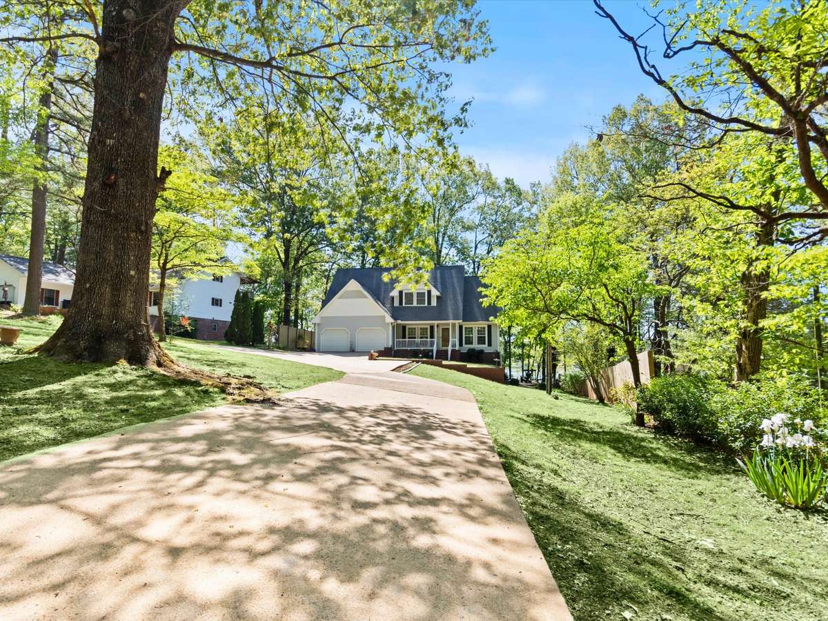 Front of house- Vinyl house, concrete driveway and sidewalks, covered front porch with railing and home entry, two car attached garage, shaded yard beautifully maintained yard