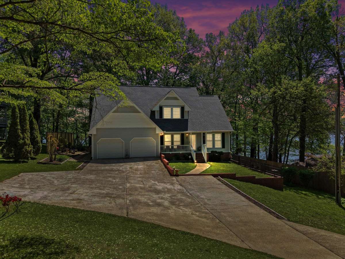 Front of house- Vinyl house, concrete driveway and sidewalks, covered front porch with railing and home entry, two car attached garage, shaded yard beautifully maintained yard