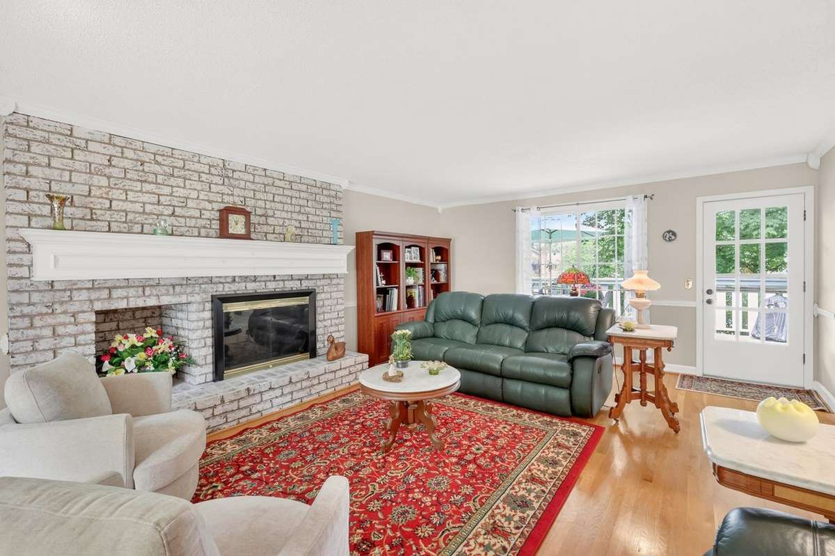 The living room is filled with natural sunlight with windows featuring views of both the front and back yards, a gas fireplace, and access to the deck.