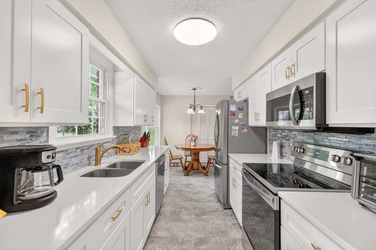 This nicely renovated kitchen has stainless appliances, quartz counters, tiled backsplash, pantry, and separate eating area.