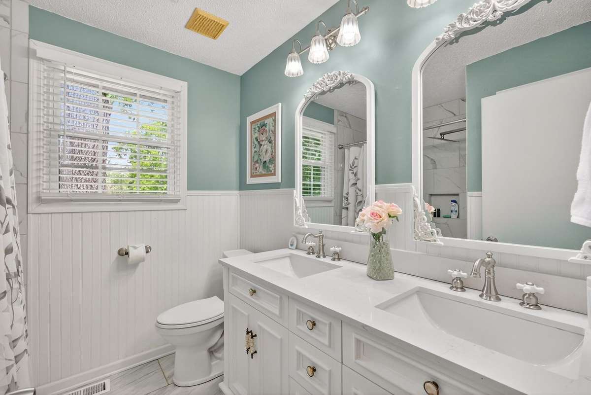 This renovated bath is on the main level and features double sinks, new tub/shower, tiled floor, and a shiplap accent wall.