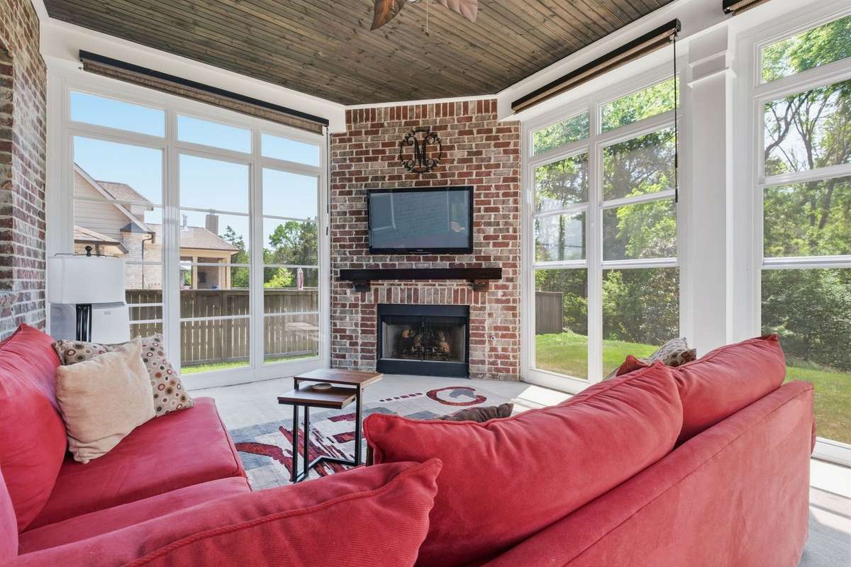 Sunroom with Wood ceiling & Brick f/p with gas logs. Get ready to watch all your fall games out here with scenic views of the woods .The windows open & converts the space into a screened porch - Portable AC & Gas logs makes this space very usable.