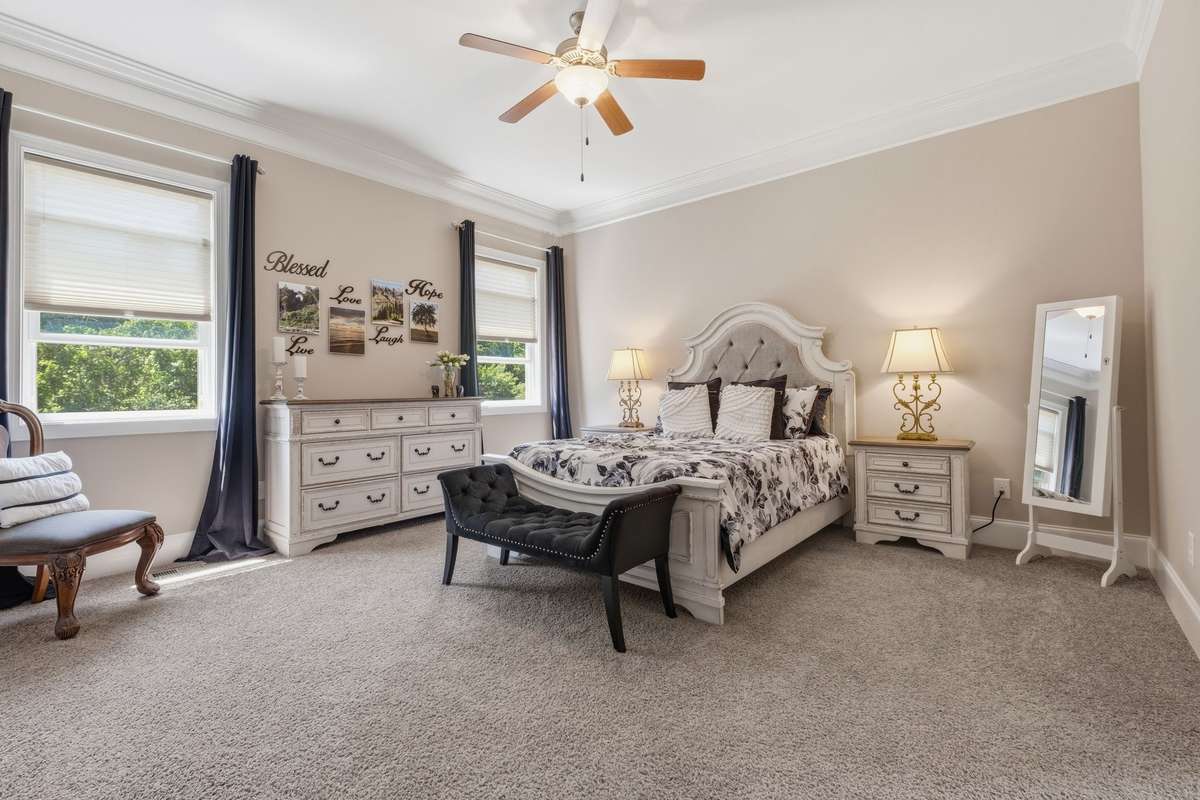 First floor Owners Suite with Neutral Colors, crown molding and huge walk in closet and view of the woods behind the house.