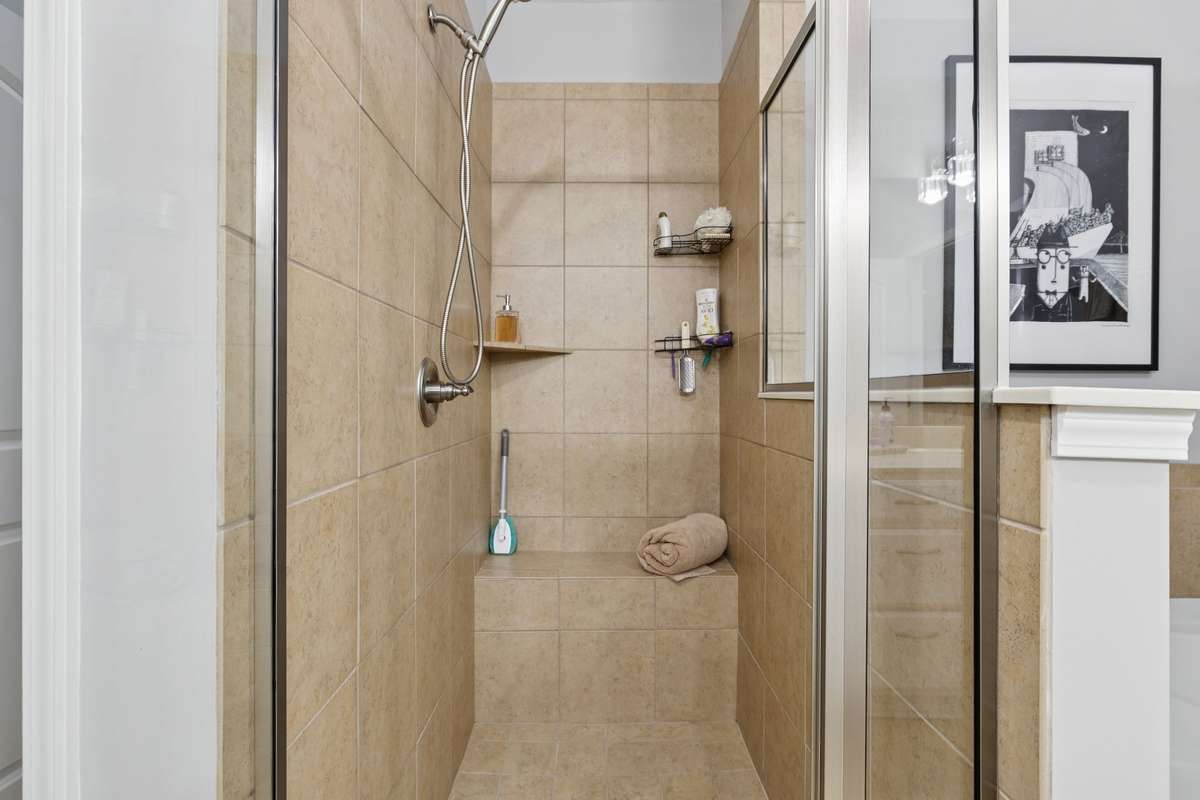 The tiled shower has a bench and built-ins + the pretty glass!